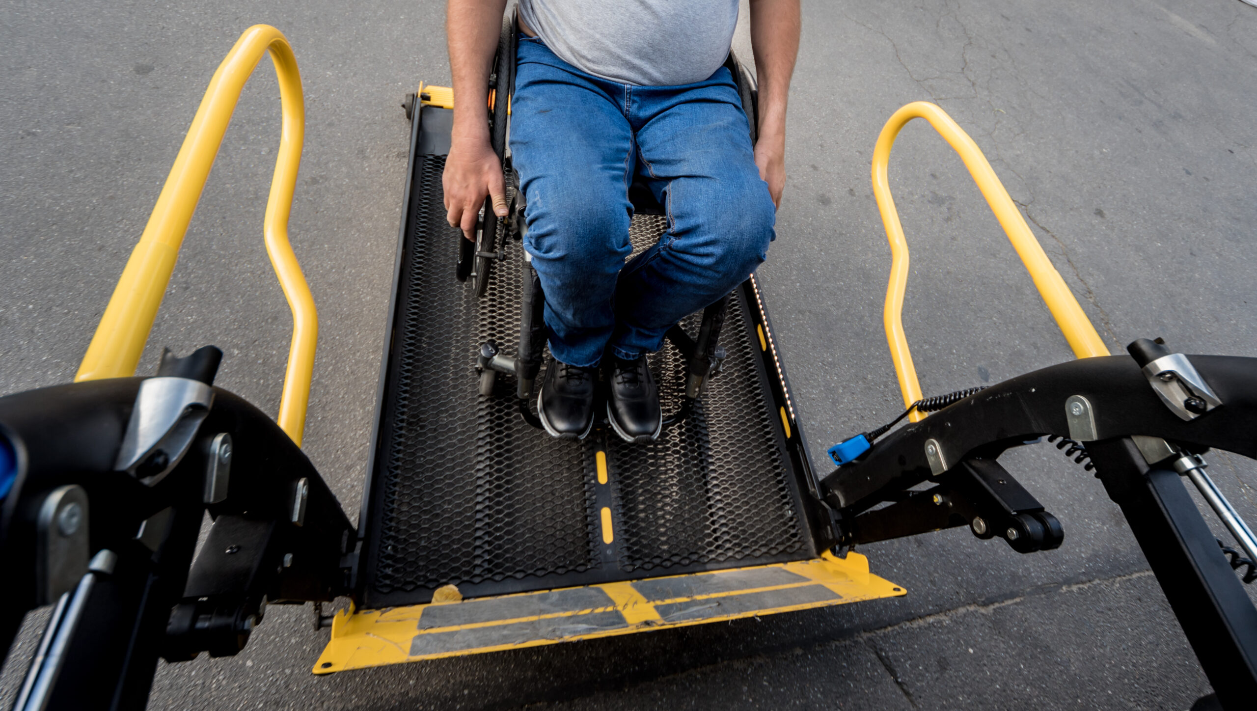 A man in a wheelchair on a lift of a specialized vehicle for people with disabilities